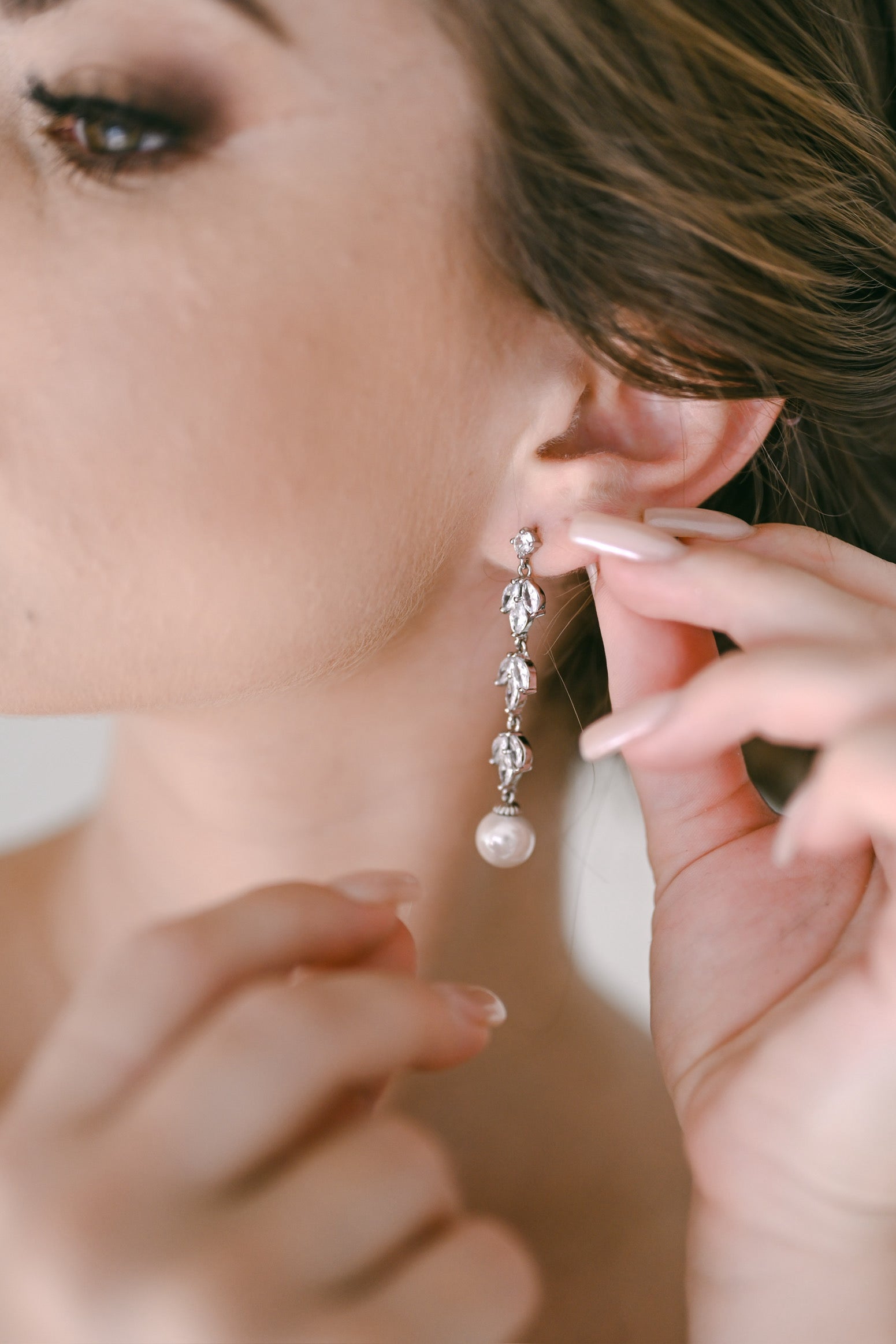 Bride wearing silver dangling earring with cubic zirconia and faux pearl