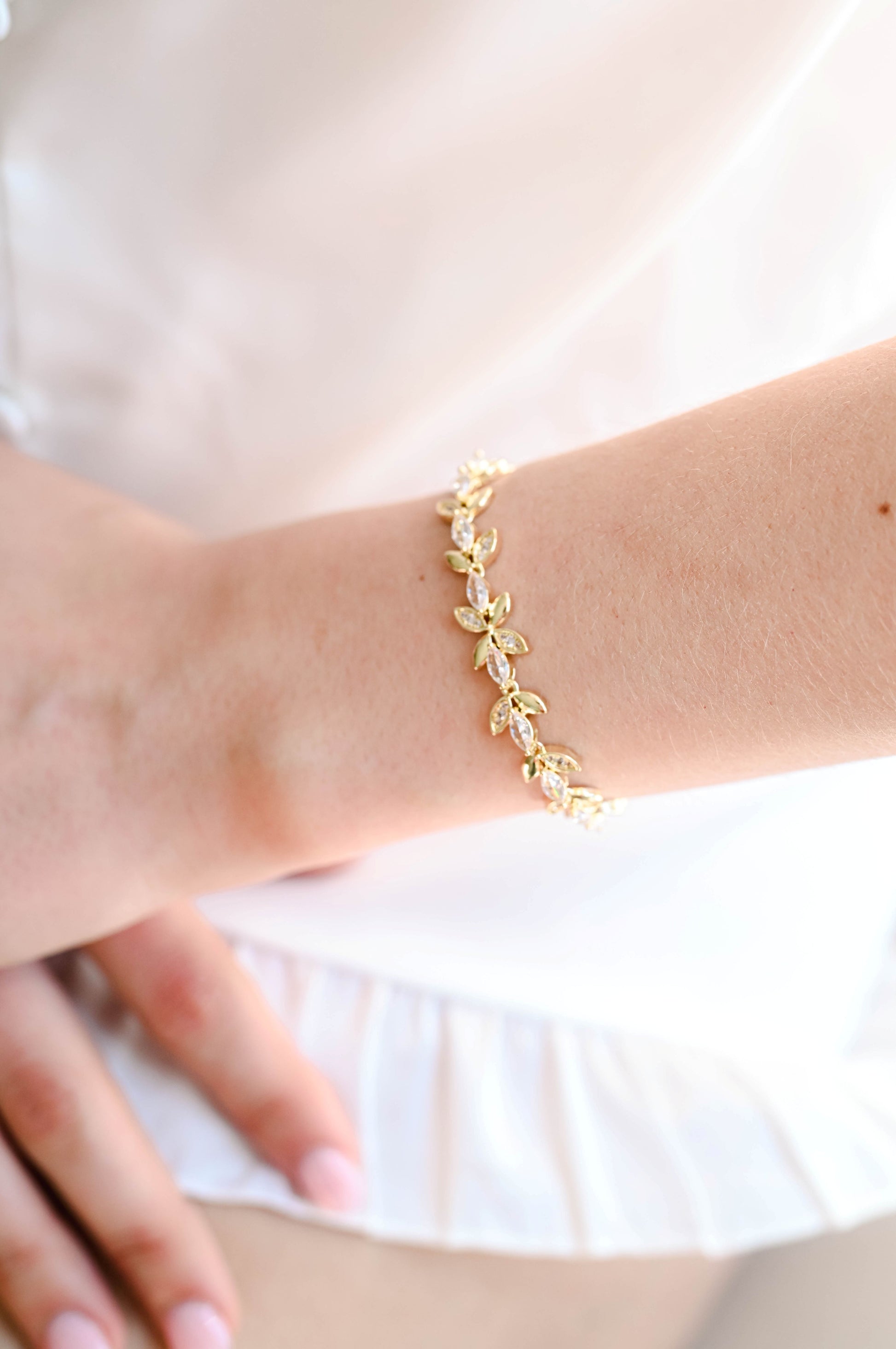 Bride wearing a gold bracelet with cubic zirconia leaf design.