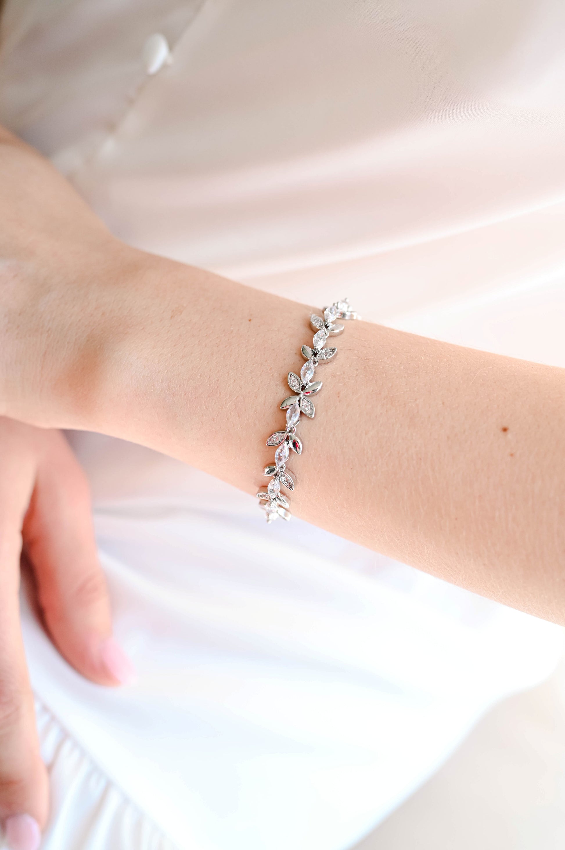 Bride wearing a silver bracelet with cubic zirconia leaf design.