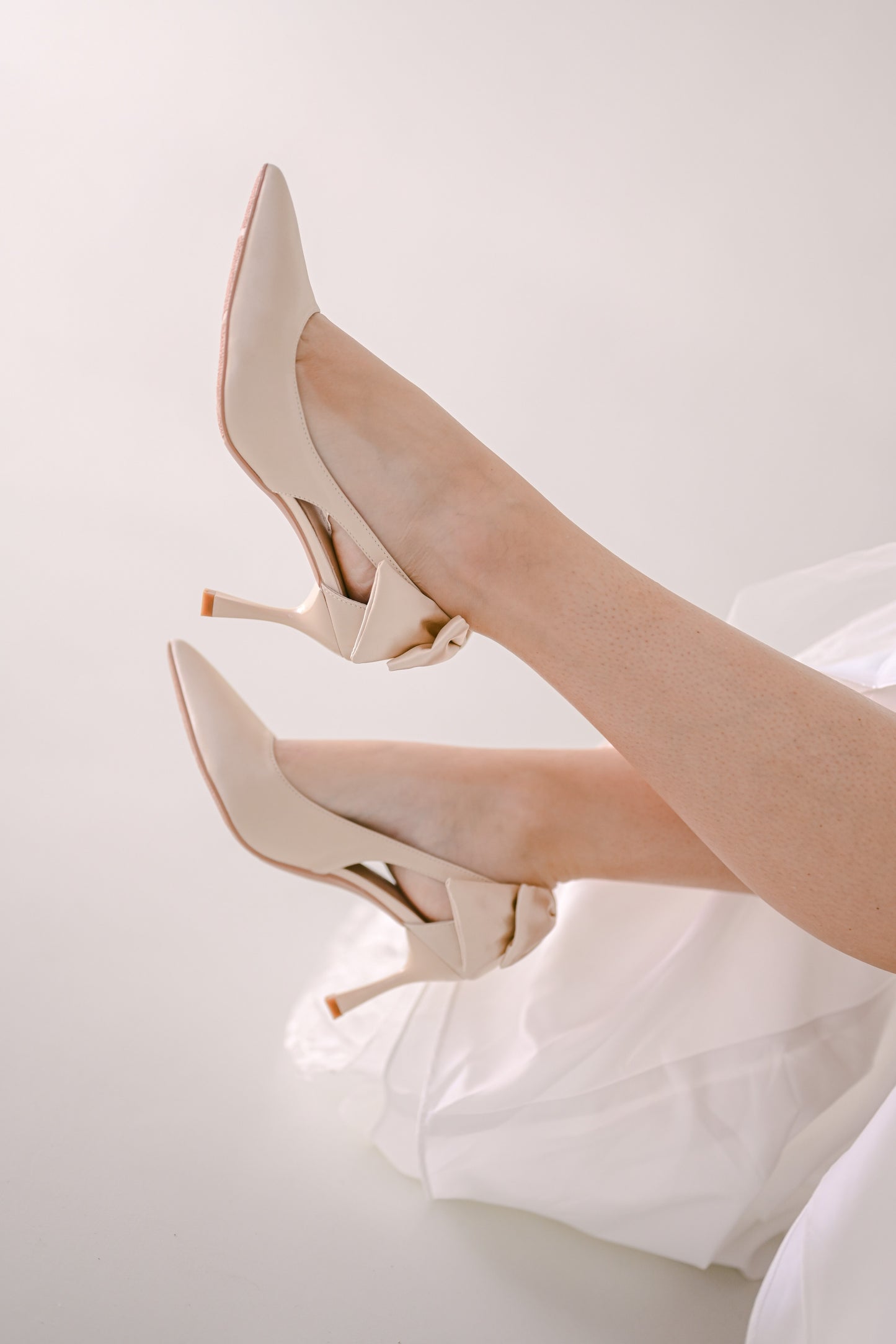 Bride wearing beige satin heels with bows at the back