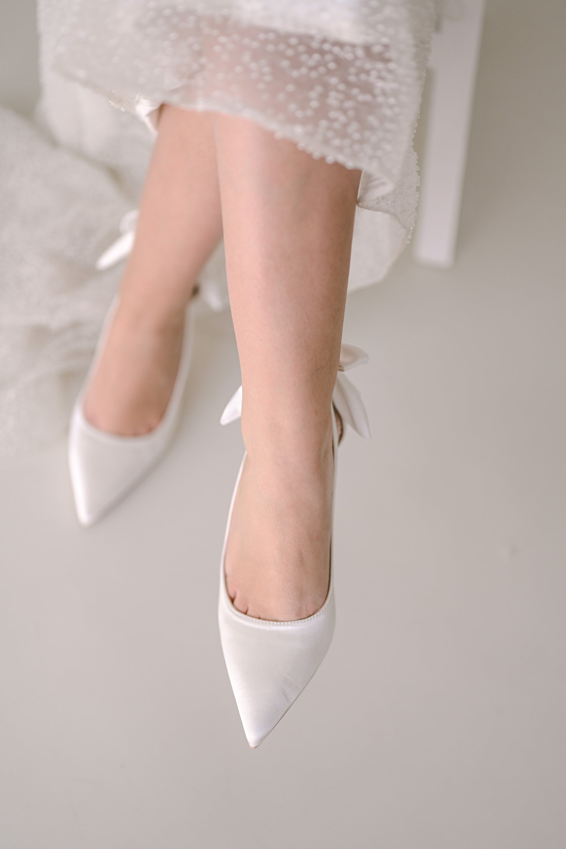 Bride wearing satin bridal heels with bows at the back