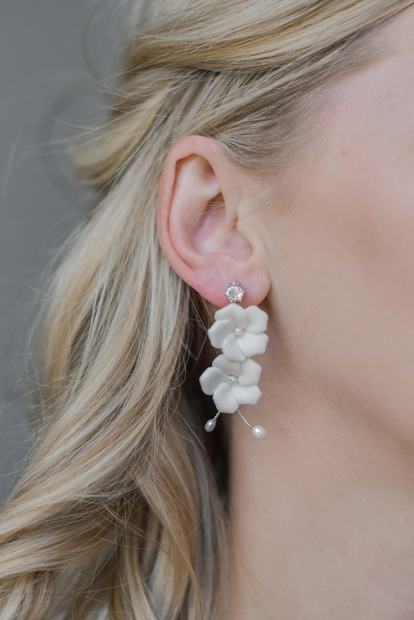 Woman wearing bridal earrings with porcelain flowers and fresh water pearls