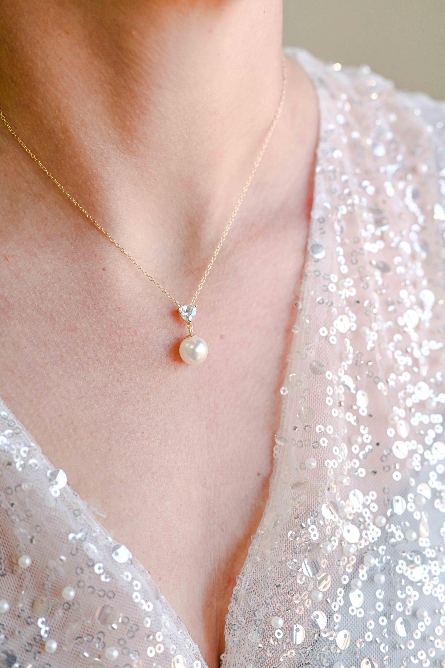 Bride wearing sterling silver, gold plated necklace with a triangle cubic zirconia and pearl detail.