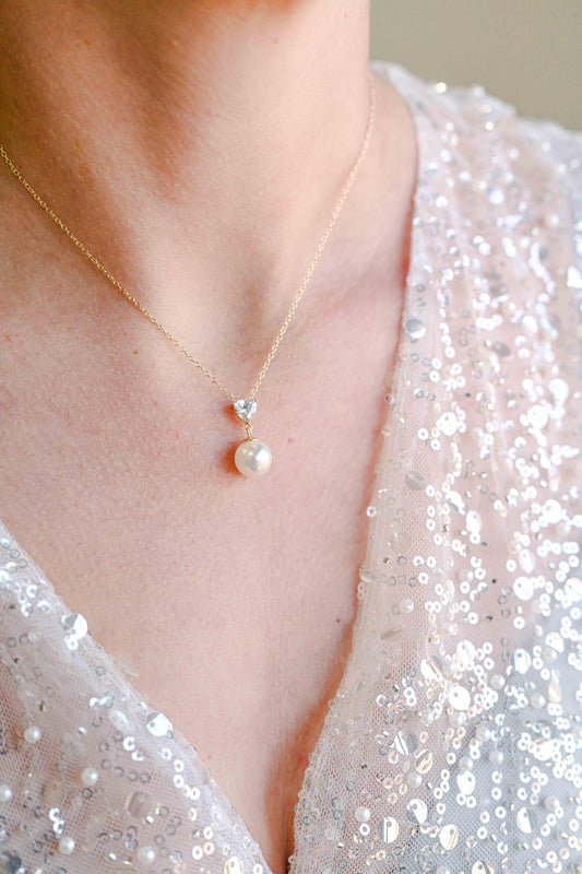 Bride wearing sterling silver, gold plated necklace with a triangle cubic zirconia and pearl detail.