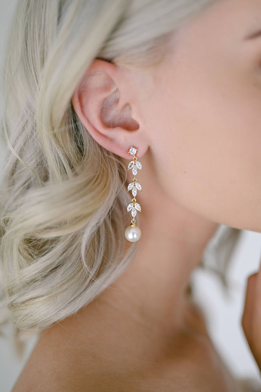 Bride wearing gold dangling earring with cubic zirconia and faux pearl