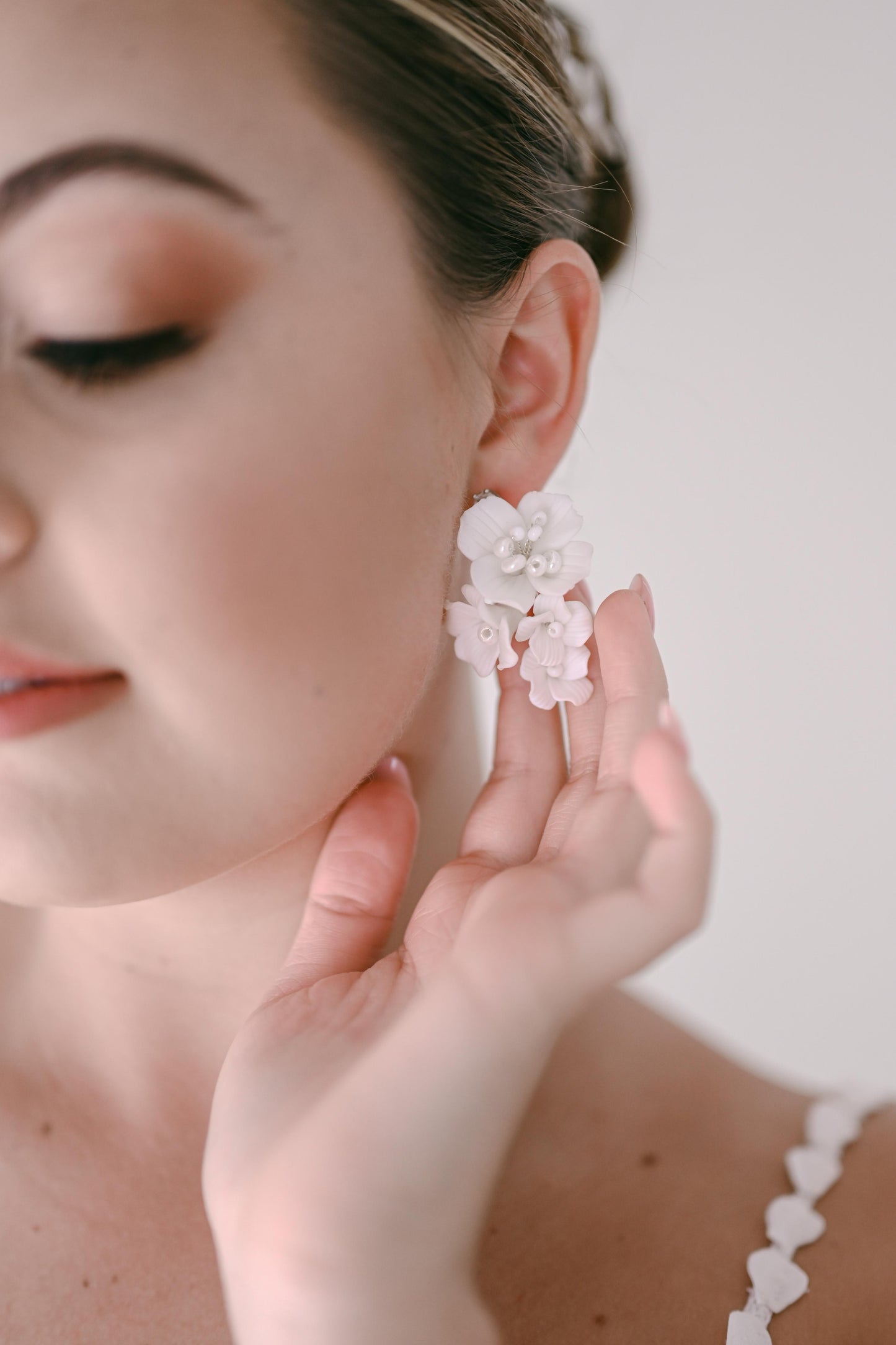 Bride wearing an earring with a cluster of porcelain flowers