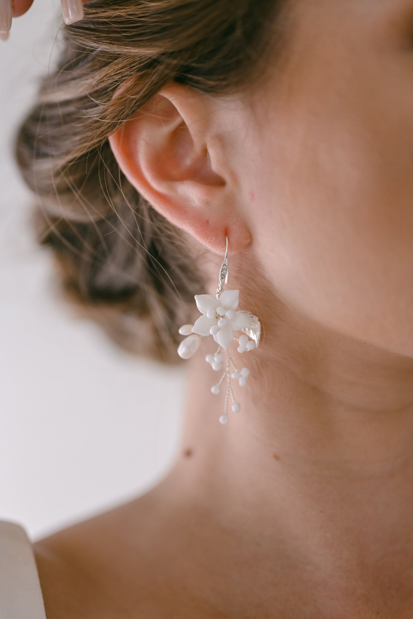 Bride wearing silver earring with porcelain flower and fresh water pearls
