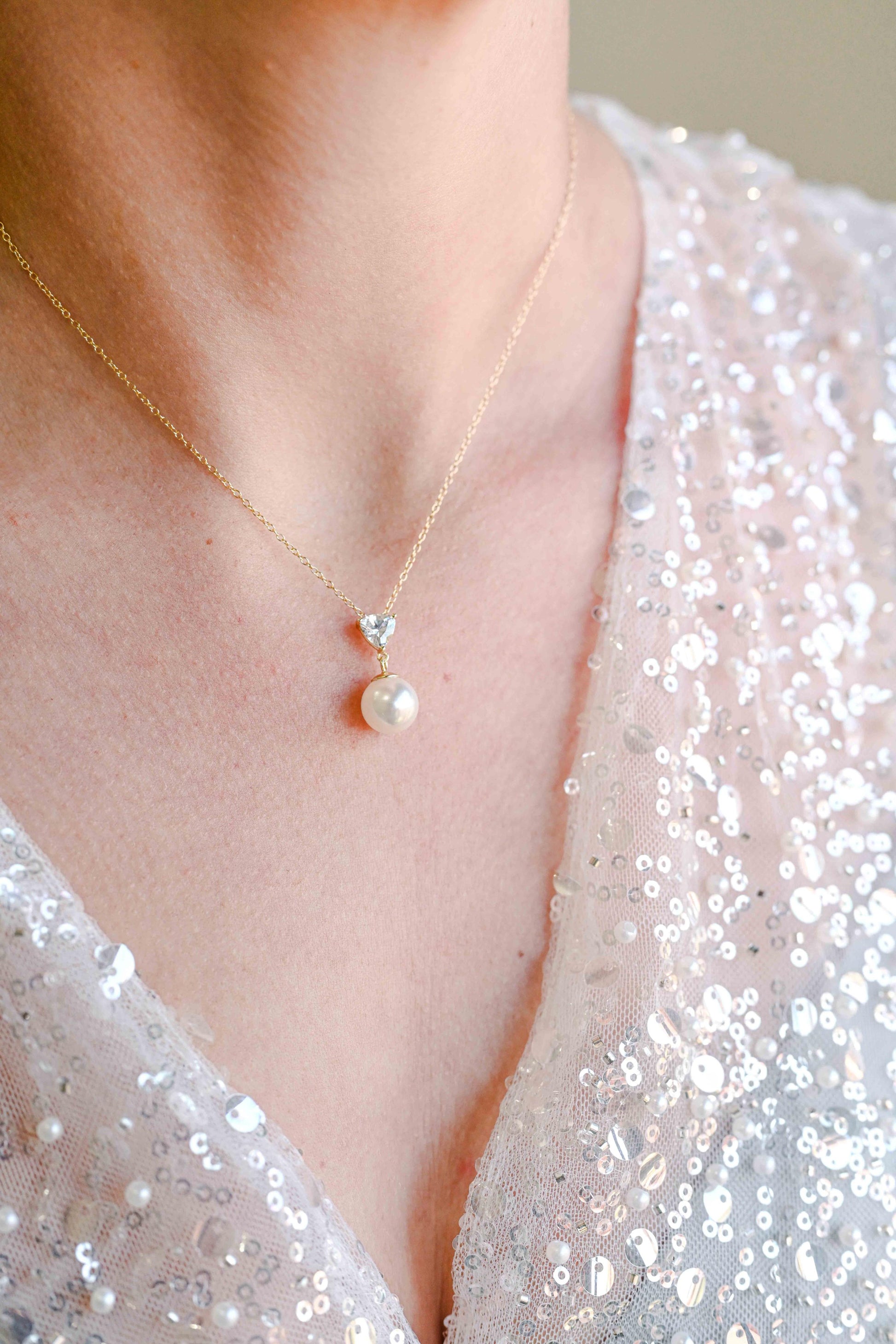Bride wearing sterling silver, gold plated necklace with a triangle cubic zirconia and pearl detail.