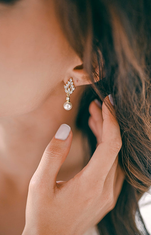 Bride wearing a gold earring with cubic zirconia and pearl detail