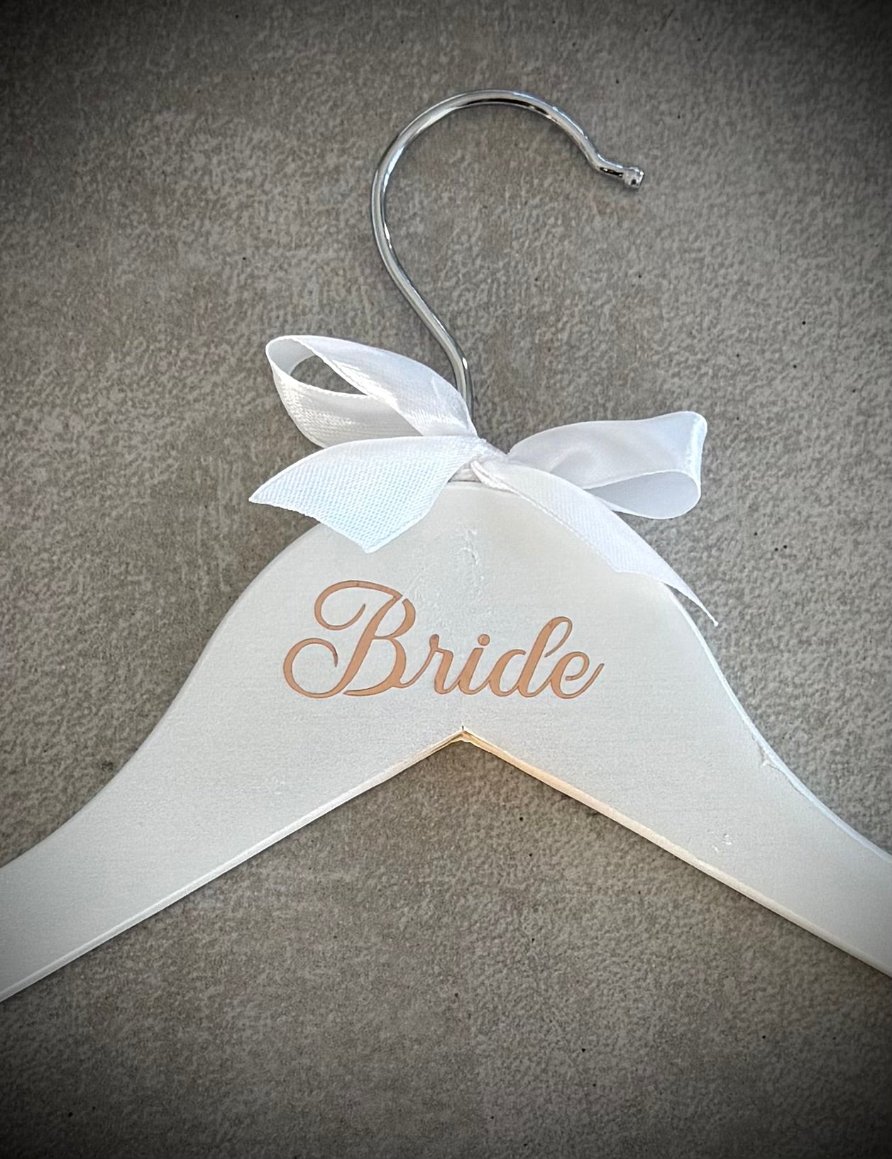 White wooden hanger with rose gold Bride vinyl and a white ribbon bow