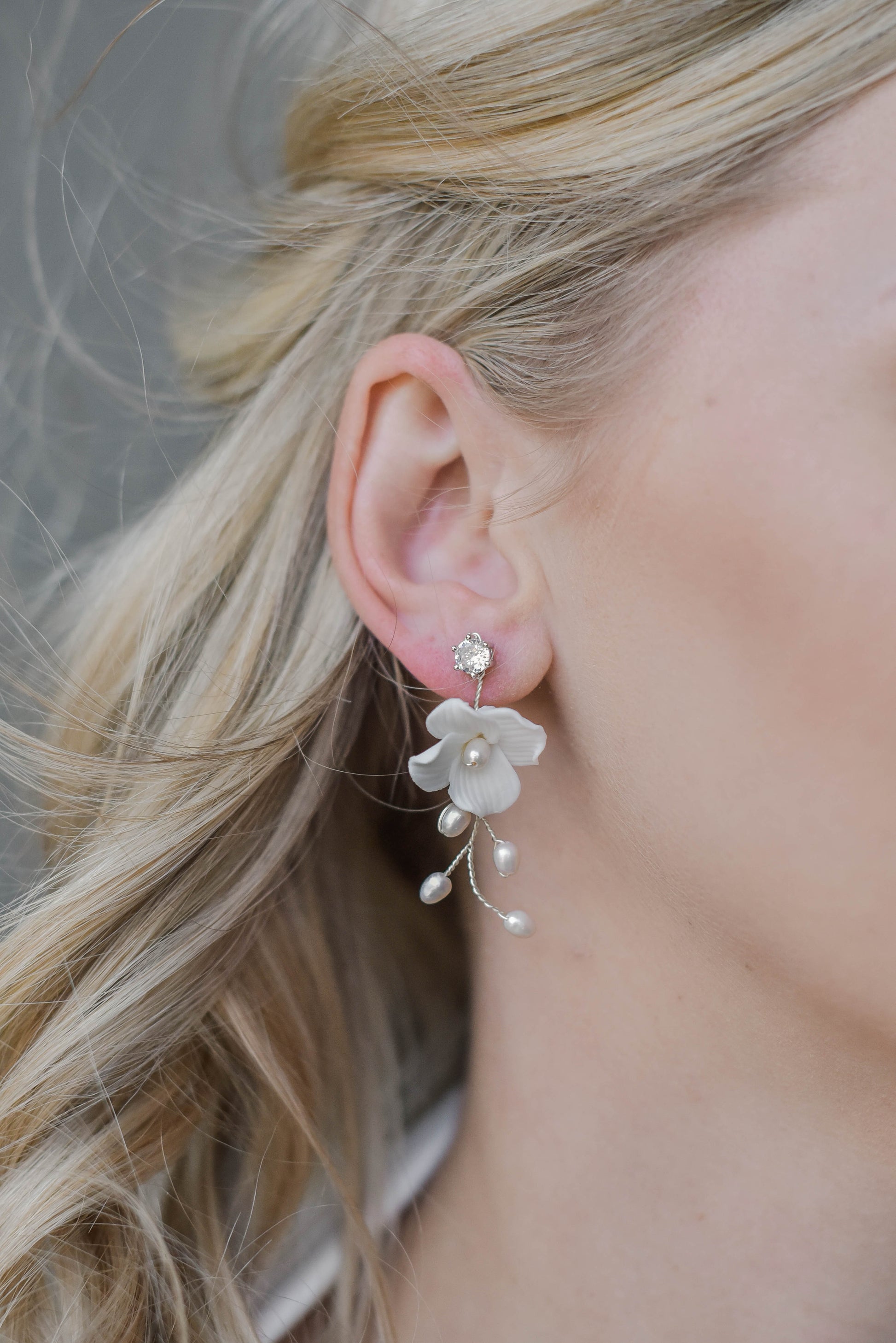 Bride wearing silver earring with porcelain flower and fresh water pearls