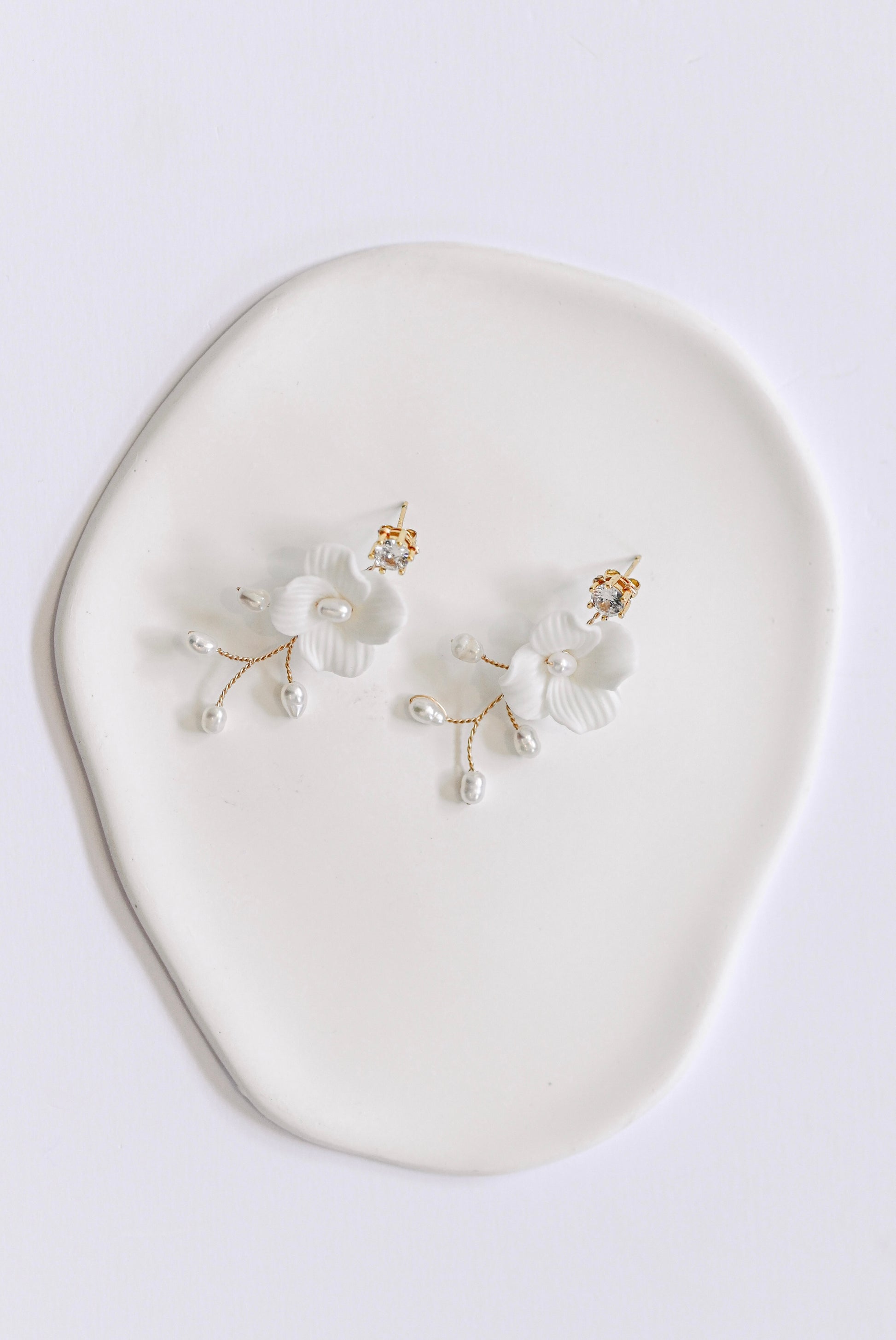 Gold bridal earring with single porcelain flower and fresh water pearls.