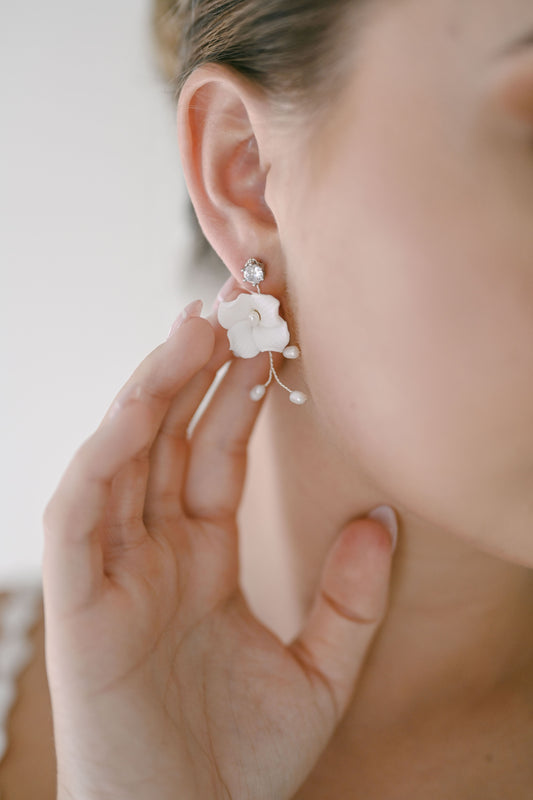 Bride wearing earring with single porcelain flower and fresh water pearls