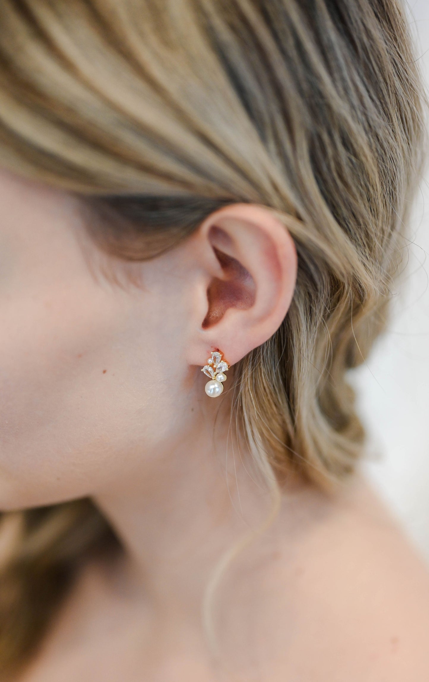 Bride wearing dainty gold stud earring with cubic zirconia and pearls